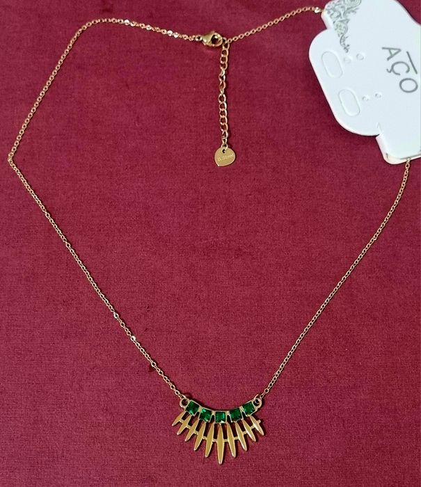 Colar dourado, em aço, com 5 pedrinhas quadradas verdes. Tem extensor.