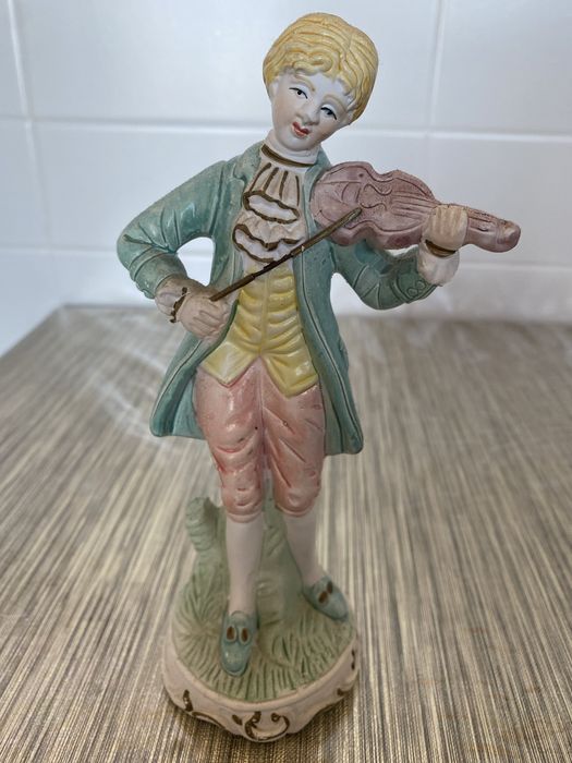 Estátua em cerâmica de um homem que segura um violino