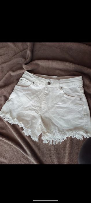 Białe strzępione spodenki