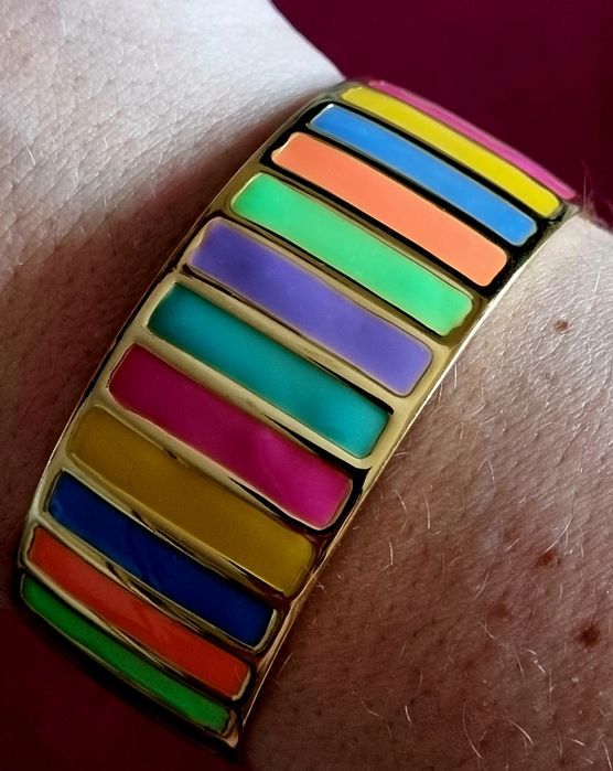 Pulseira dourada, em aço, com riscas coloridas. Fácil colocação.