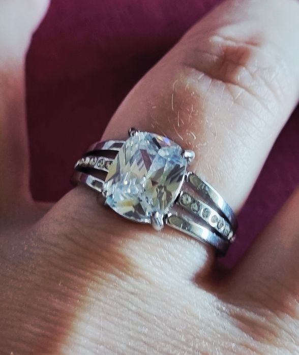 Anel prateado, em aço, com ponto de luz oval e 1 fiada de zirconias.18