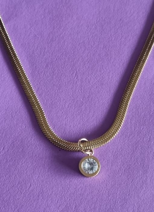 Colar dourado, em aço, malha fita com ponto de luz. Tem extensor