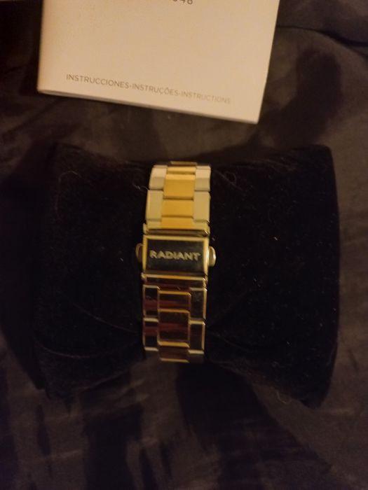 Relógio prateado e dourado com zirconias à volta do mostrador.