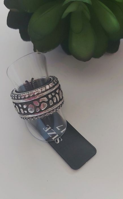 Anel prateado, em aço, com zirconias. Fundo preto. T17