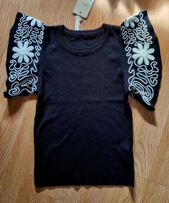 Camisola em malha preta com mangas abalonadas bordadas a branco. TU
