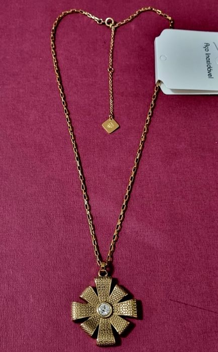 Colar dourado, em aço, com flor trabalhada e um ponto de luz central.