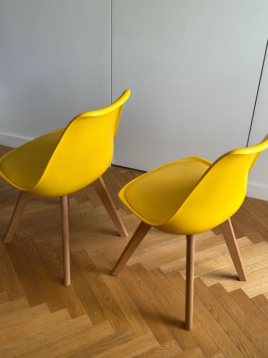 Dwa żółte krzesła na drewnianych nogach skandynawski styl