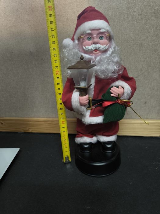 Pai Natal com candeeiro e saco de presentes com música.
Figura decorat