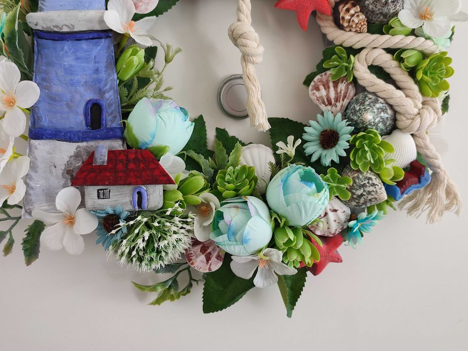 Guirlanda artesanal marítima com flores, conchas e farol decorativo