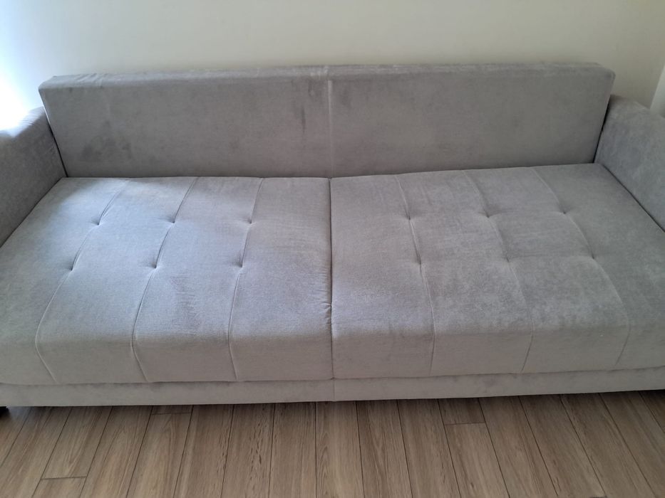 Szara sofa rozkładana z pojemnikiem na pościel