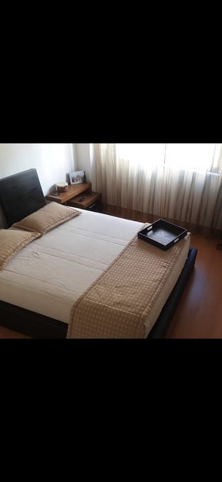 Cama casal com mesas de cabeceiras com colcha e almofadas
