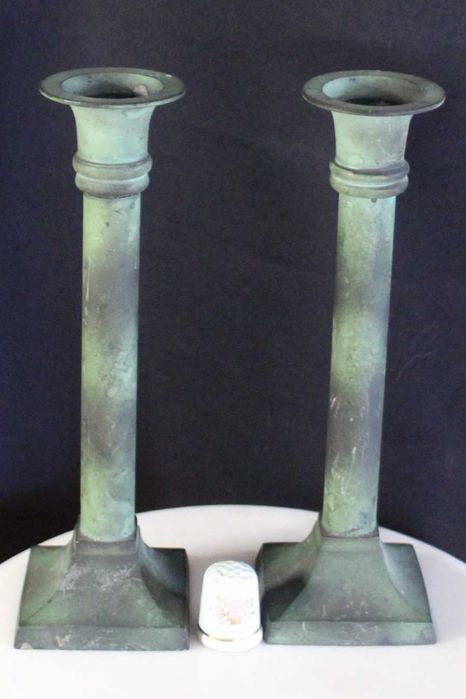 Par de castiçais antigos de latão com pátina esverdeada.