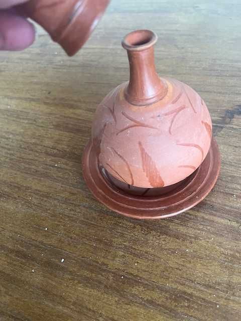 Garrafa pequena de barro com prato e copo