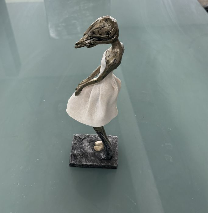 Peça decorativs em formato de mulher com o cabelo a fugir com o vento.