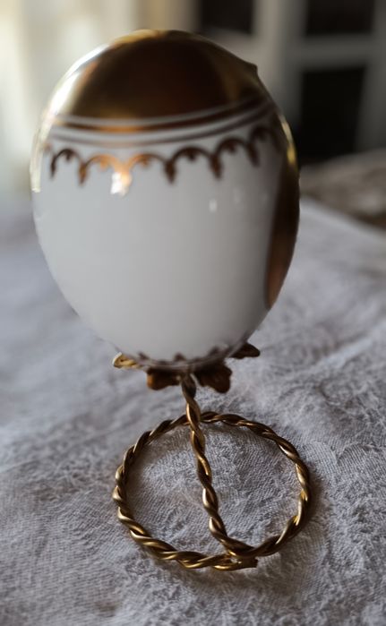 Ovo de Páscoa de porcelana com decorações douradas.Assente num suporte