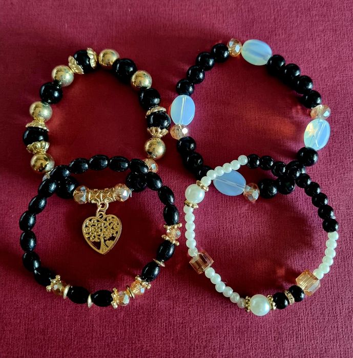 Conjunto de 4 pulseiras elásticas em tons de preto e dourado.