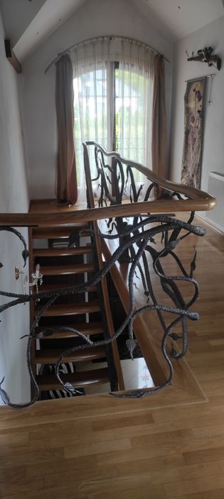 Piękne dębowe schody z kuta barierka i giętą poręczą
