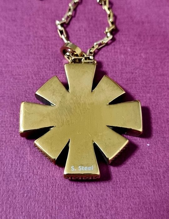 Colar dourado, em aço, com flor trabalhada e um ponto de luz central.