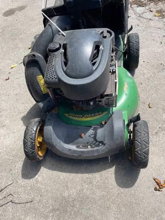 Máquina de cortar relva a gasolina, marca John Deere a funcionar em pleno