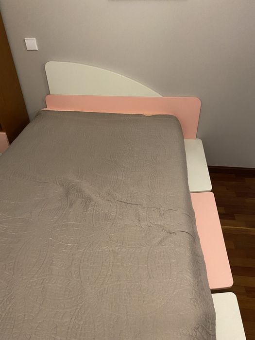 Cama em tons rosa e branco com suporte lateral