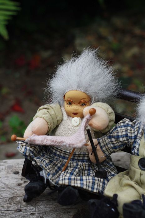 Dwie lalki siedzące na ławce Babcia i Dziadek