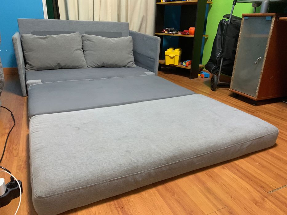 Sofá cama cinza com uma pequena quemadura