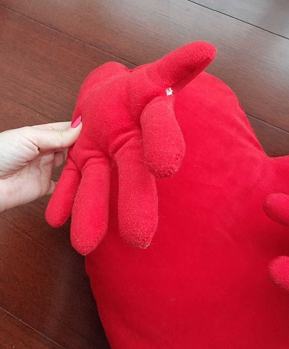 Almofada vermelha em formato de coração com os braços abertos