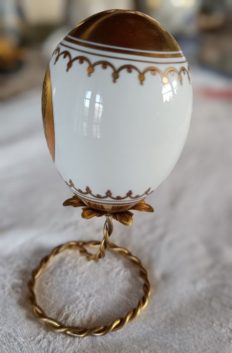 Ovo de Páscoa de porcelana com decorações douradas.Assente num suporte
