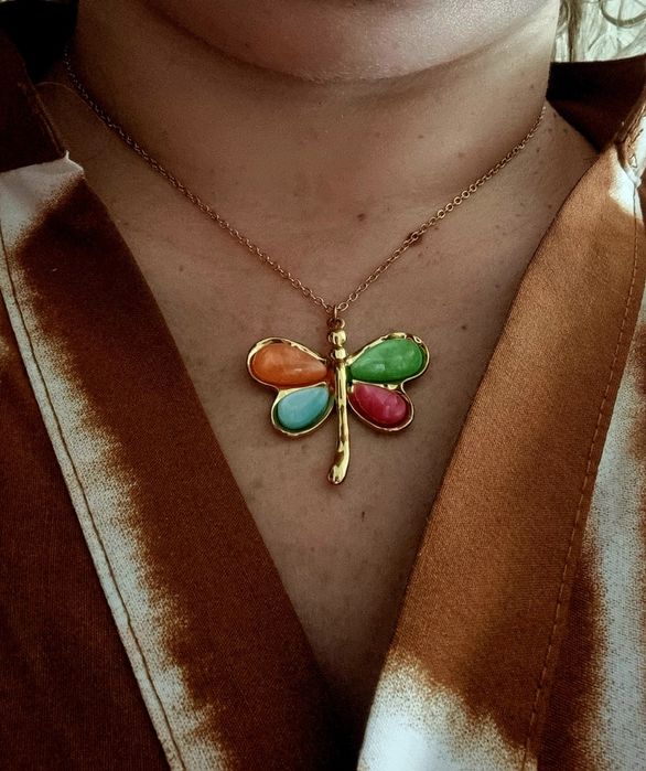 Colar dourado, em aço, com libelinha colorida. Tem extensor