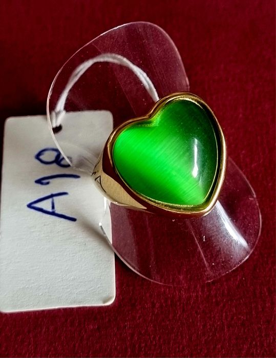 Anel dourado, em aço, em forma de coração verde. T18