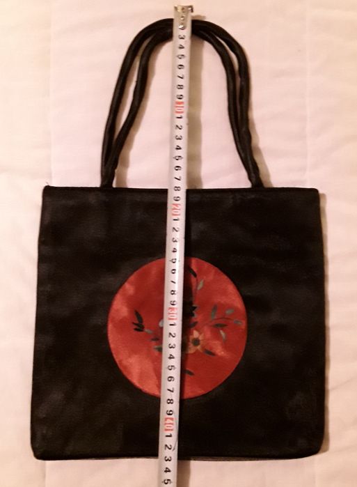 Bolsa ou mala de mão preta com aplicação circular vermelha