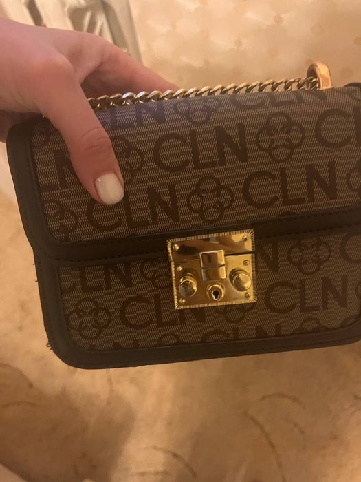 коричневая сумка через плечо с монограммой и золотой фурнитурой.