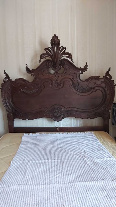 Cama casal com cabecera e estructura de madeira maciça e esculpida.
