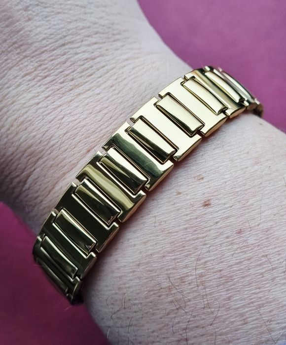Pulseira elástica, dourada, em aço inoxidável.