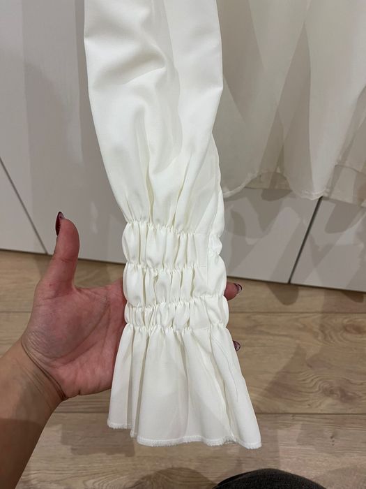 Blusa branca de manga comprida com elasticos na manga e costas abertas