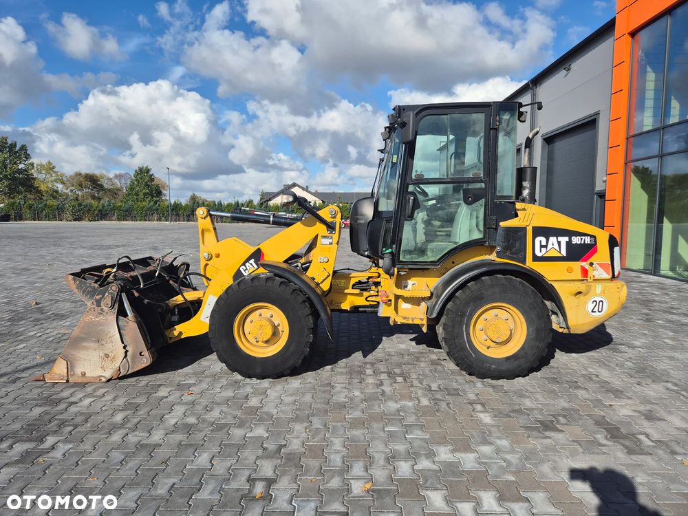 Caterpillar 907H / z Niemiec / Łyżka otwierana + Widły / 6700 mth / - 2
