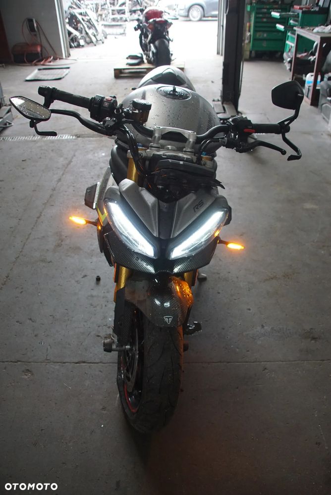 Triumph Speed Triple 1200 rs 2022 na części 692106889 SILNIK: silnik kompletny, blok silnika, głowica cylindrów, pokrywa zaworów, uszczelka głowicy, cylinder, tuleja cylindra, tłok, pierścienie tłokowe, sworzeń tłoka, korbowód, wał korbowy, panewki wału, wałek rozrządu, koło rozrządu, łańcuch rozrządu, napinacz rozrządu, ślizg rozrządu, zawór ssący, zawór wydechowy, sprężyna zaworowa, popychacz zaworu, dźwigienka zaworowa, uszczelniacz zaworowy, miska olejowa, korek spustowy oleju, pompa oleju, smok olejowy, filtr oleju, chłodnica oleju, przewód olejowy, obudowa filtra oleju, czujnik ciśnienia oleju, pokrywa alternatora, pokrywa sprzęgła, dekiel silnika, uszczelki silnika, engine assembly, engine block, cylinder head, valve cover, piston, piston rings, connecting rod, crankshaft, camshaft, timing chain, oil pump.  UKŁAD PALIWOWY I DOLOTOWY: zbiornik paliwa, bak paliwa, korek wlewu paliwa, pompa paliwa, kosz pompy paliwa, filtr paliwa, przewód paliwowy, listwa wtryskowa, wtryskiwacz, regulator ciśnienia paliwa, przepustnica, korpus przepustnicy, silniczek krokowy, czujnik położenia przepustnicy TPS, manetka gazu, rolgaz, elektroniczny gaz ride-by-wire, airbox, obudowa filtra powietrza, filtr powietrza, króciec dolotowy, kolektor dolotowy, czujnik temperatury powietrza, czujnik ciśnienia MAP, fuel tank, fuel pump, fuel injector, throttle body, air filter.  SPRZĘGŁO I SKRZYNIA BIEGÓW: kosz sprzęgłowy, piasta sprzęgła, tarcze sprzęgłowe, przekładki sprzęgła, sprężyny sprzęgła, docisk sprzęgła, pompa sprzęgła, wysprzęglik, przewód sprzęgła, klamka sprzęgła, skrzynia biegów, wałek sprzęgłowy, wałek zdawczy, koła zębate skrzyni, wodzik zmiany biegów, bęben zmiany biegów, czujnik biegu, dźwignia zmiany biegów, cięgno zmiany biegów, quickshifter, czujnik quickshiftera, clutch basket, clutch plates, gearbox, transmission shaft, gear selector drum, shift fork.  NAPĘD TYLNEGO KOŁA: zębatka przednia, zębatka tylna, łańcuch napędowy, spinka łańcucha, napinacz łańcucha, prowadnica łańcucha, osłona łańcucha, guma zabieraka, zabierak zębatki, mocowanie zębatki, front sprocket, rear sprocket, drive chain, chain adjuster, chain guide, chain guard, sprocket carrier.  UKŁAD WYDECHOWY: kolektory wydechowe, rury wydechowe, tłumik końcowy, tłumik środkowy, katalizator, osłona tłumika, zawór wydechowy, silniczek zaworu wydechowego, linki zaworu wydechowego, sonda lambda, uszczelka kolektora, obejma wydechu, mocowanie tłumika, exhaust headers, muffler, silencer, catalytic converter, exhaust valve, oxygen sensor, heat shield.  UKŁAD CHŁODZENIA: chłodnica, wentylator chłodnicy, osłona chłodnicy, korek chłodnicy, zbiorniczek wyrównawczy, pompa wody, termostat, obudowa termostatu, przewód chłodnicy, wąż układu chłodzenia, króciec wody, czujnik temperatury płynu, radiator, radiator fan, coolant reservoir, water pump, thermostat, coolant hose.  ZAWIESZENIE PRZEDNIE: lagi przednie, widelec przedni, goleń widelca, rura nośna, dolna półka, górna półka, sztyca widelca, uszczelniacz lagi, uszczelniacz przeciwpyłowy, sprężyna widelca, kartridż amortyzatora, regulator tłumienia, korek lagi, olej do lag, amortyzator skrętu, steering damper, front fork, fork tube, fork seal, fork cartridge, triple clamp, upper yoke, lower yoke.  ZAWIESZENIE TYLNE: amortyzator tylny, sprężyna amortyzatora, wahacz jednoramienny, oś wahacza, łożysko wahacza, kiwak zawieszenia, łącznik amortyzatora, regulator napięcia wstępnego, mocowanie amortyzatora, rear shock, shock absorber, single-sided swingarm, swingarm pivot, suspension linkage.  UKŁAD HAMULCOWY: zacisk hamulcowy przedni lewy, zacisk hamulcowy przedni prawy, zacisk hamulcowy tylny, jarzmo zacisku, tłoczek hamulcowy, zestaw naprawczy zacisku, klocki hamulcowe przednie, klocki hamulcowe tylne, tarcza hamulcowa przednia, tarcza hamulcowa tylna, pompa hamulcowa przednia, pompa hamulcowa tylna, przewód hamulcowy, przewód w oplocie, zbiorniczek płynu hamulcowego, klamka hamulca, pedał hamulca, czujnik światła stop, moduł ABS, pompa ABS, czujnik ABS, pierścień ABS, front brake caliper, rear brake caliper, brake pads, brake disc, brake rotor, brake master cylinder.  KOŁA I OPONY: felga przednia, felga tylna, koło przednie, koło tylne, oś koła przedniego, oś koła tylnego, dystans koła, łożysko koła, uszczelniacz koła, piasta koła, nakrętka tylnego koła, zawór opony, czujnik ciśnienia TPMS, opona przednia, opona tylna, front wheel, rear wheel, wheel rim, wheel axle, wheel bearing, wheel hub, tire, tyre, TPMS sensor.  KIEROWNICA I STEROWANIE: kierownica, mocowanie kierownicy, riser kierownicy, lewa manetka, prawa manetka, ciężarki kierownicy, końcówki kierownicy, lusterko lewe, lusterko prawe, uchwyt lusterka, klamka sprzęgła, klamka hamulca, przełącznik zespolony lewy, przełącznik zespolony prawy, rolgaz, stacyjka, antena stacyjki, amortyzator skrętu, handlebar, handlebar clamp, grip, bar end, rear-view mirror, switchgear, ignition switch.  RAMA I PODWOZIE: rama główna, rama tylna, subframe, wspornik ramy, mocowanie silnika, śruba mocowania silnika, crash pad, slider ramy, osłona ramy, stopka boczna, czujnik stopki bocznej, sprężyna stopki, uchwyt tablicy rejestracyjnej, mocowanie podnóżka, podnóżek kierowcy lewy, podnóżek kierowcy prawy, podnóżek pasażera lewy, podnóżek pasażera prawy, set podnóżków, rearset, frame, rear subframe, engine mount, crash protector, side stand, footpeg.  OWIEWKI I NADWOZIE: owiewka przednia, owiewka boczna lewa, owiewka boczna prawa, owiewka tylna, boczek lewy, boczek prawy, osłona chłodnicy, osłona silnika, belly pan, pług pod silnik, błotnik przedni, błotnik tylny, nadkole, hugger, przednia szyba, szyba sportowa, deflektor, wlot powietrza, osłona ramy, osłona wahacza, osłona karbonowa, carbon cover, fairing, side panel, front fender, rear fender, windscreen, radiator cover.  SIEDZENIE I TYLNA CZĘŚĆ: siedzenie kierowcy, siedzenie pasażera, kanapa, zamek siedzenia, linka zamka siedzenia, uchwyt pasażera, ogon motocykla, stelaż tylny, wypełnienie zadupka, osłona siedzenia, seat cowl, rider seat, passenger seat, seat lock, tail section.  ELEKTRYKA I ELEKTRONIKA: wiązka elektryczna główna, wiązka przednia, wiązka tylna, sterownik silnika ECU, moduł zapłonowy, regulator napięcia, alternator, stator, rotor alternatora, rozrusznik, przekaźnik rozrusznika, akumulator, skrzynka bezpieczników, bezpiecznik, przekaźnik, cewka zapłonowa, świeca zapłonowa, fajka świecy, przewód masowy, złącze elektryczne, gniazdo USB, immobilizer, antena immobilizera, czujnik przechyłu, czujnik położenia wału, czujnik położenia wałka, czujnik prędkości, czujnik temperatury, czujnik ciśnienia, wiring harness, ECU, voltage regulator, alternator, starter motor, starter relay, battery, fuse box, ignition coil, spark plug.  OŚWIETLENIE I ZEGARY: reflektor przedni, lampa przednia LED, światło mijania, światło drogowe, moduł reflektora, kierunkowskaz przedni lewy, kierunkowskaz przedni prawy, kierunkowskaz tylny lewy, kierunkowskaz tylny prawy, lampa tylna, światło stop, lampka tablicy rejestracyjnej, licznik, zegary, wyświetlacz TFT, panel wskaźników, obudowa licznika, czujnik poziomu paliwa, headlight, LED headlamp, tail light, brake light, turn signal, indicator, instrument cluster, dashboard, TFT display.  SYSTEMY ELEKTRONICZNE: moduł kontroli trakcji, traction control, czujnik IMU, moduł ride-by-wire, tempomat, przełącznik tempomatu, quickshifter up and down, moduł ABS, czujnik kąta pochylenia, moduł Bluetooth, antena, moduł bezkluczykowy, keyless module, kluczyk, pilot, immobilizer key, przełącznik trybów jazdy, riding mode switch.  ŚRUBY, ŁOŻYSKA I DROBNE CZĘŚCI: komplet śrub, śruba owiewki, nakrętka osi, tuleja dystansowa, podkładka, spinka, zatrzask, kołek montażowy, guma mocująca, silentblock, obejma, uchwyt przewodu, łożysko główki ramy, łożysko igiełkowe, łożysko kulkowe, simmering, uszczelka, oring, zestaw naprawczy, - 15