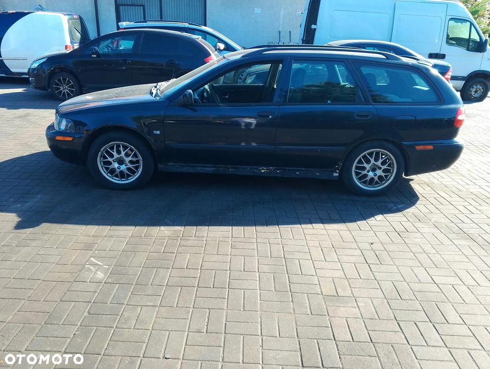 Volvo V40 I FL (99-04r.) 1.8 B 122KM. Silnik B4184S2 Skrzynia M5P lakier BLACK METALIC.Cały na części. GWARANCJA !!!  Przód Tył Zestaw Komplet Drzwi Klapa Zderzak Błotnik Maska Grill Atrapa Szyba Pas Lampa Lusterko Boczki Fotel Kanapa Kokpit Deska Rozdzielcza Przełącznik Włącznik Sterownik Przewody Wiązka Instalacja Moduł Komputer Czujnik Listwa Pompa Alternator Wtryski Głowica Rozrusznik Kompresor Sprzęgło Dwumas Silnik Skrzynia ABS Klimatyzacji Paliwa Wspomagania Kolektor Turbina Przepustnica Zawór Chłodnica Koło Hak Belka Sanki Zawieszenie Mcpherson Półoś Amortyzator Wydech Tłumik Zacisk Most - 4