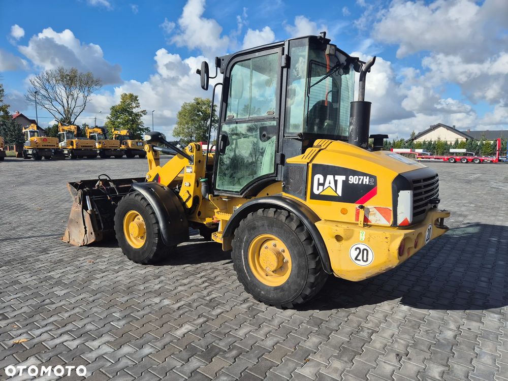 Caterpillar 907H / z Niemiec / Łyżka otwierana + Widły / 6700 mth / - 3