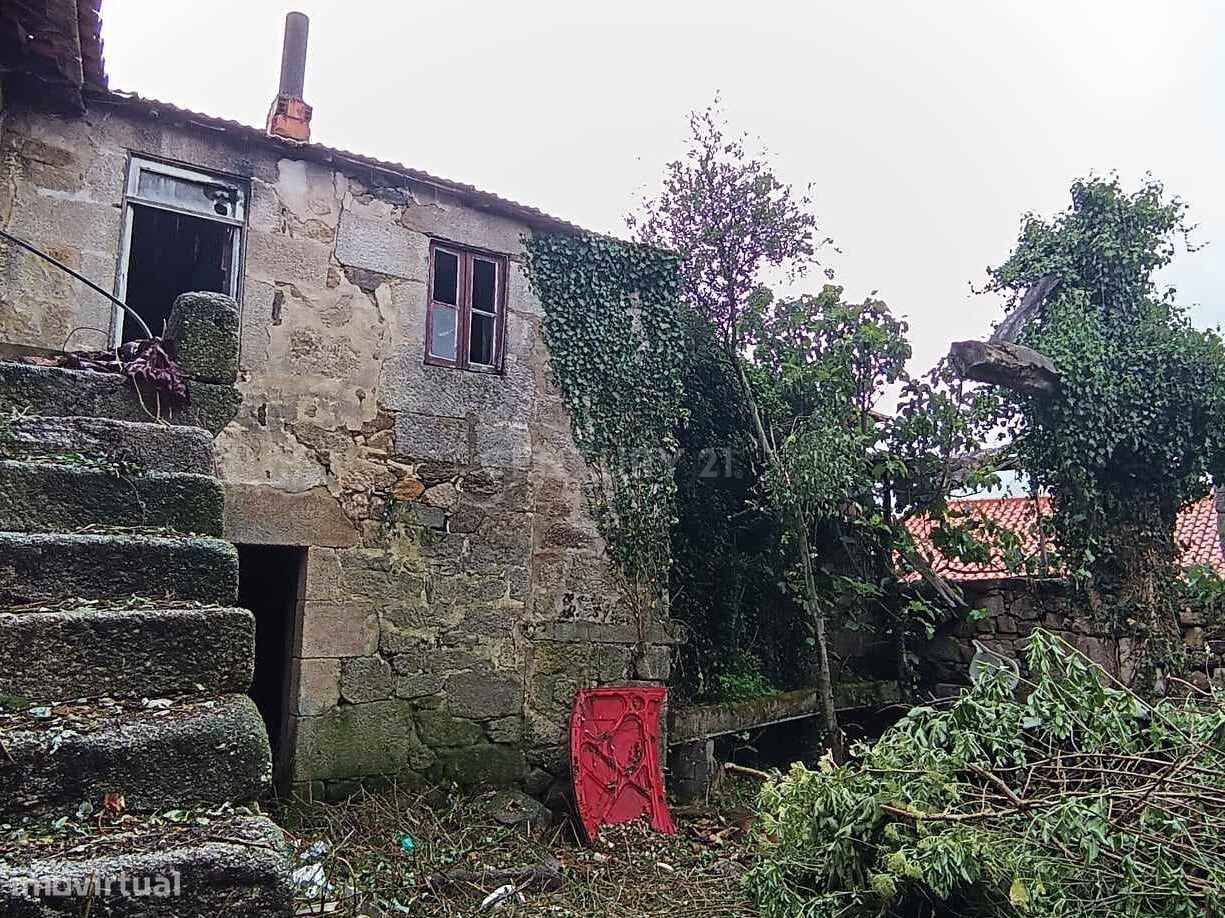 Casa de gaveto, em pedra, com pátio murado.