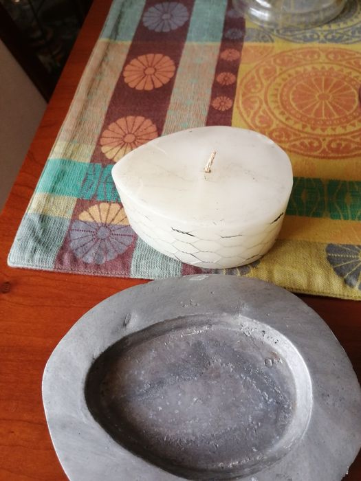 Vela branca rodeada com metal e com suporte metálico