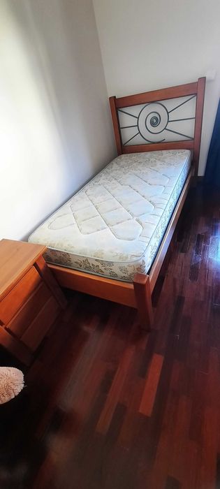 Cama de madeira com colchão e mesa de cabeceira
