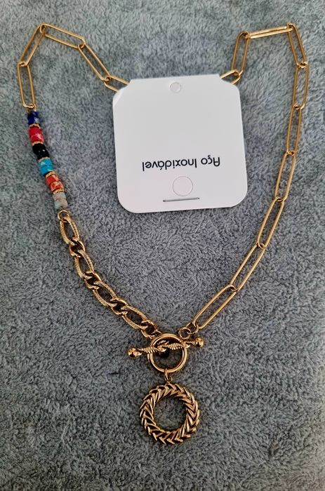 Colar dourado, em aço, assimétrico e com pedrinhas naturais coloridas.