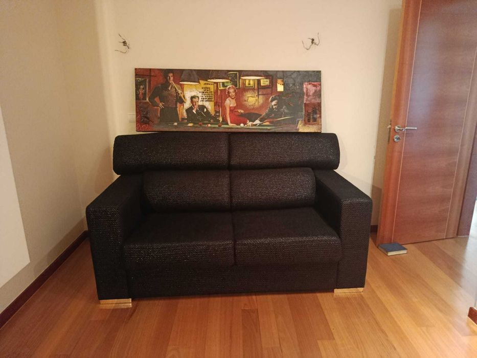 Sofa-cama em tecido preto e prata, encosto rebativel e pés inox polido