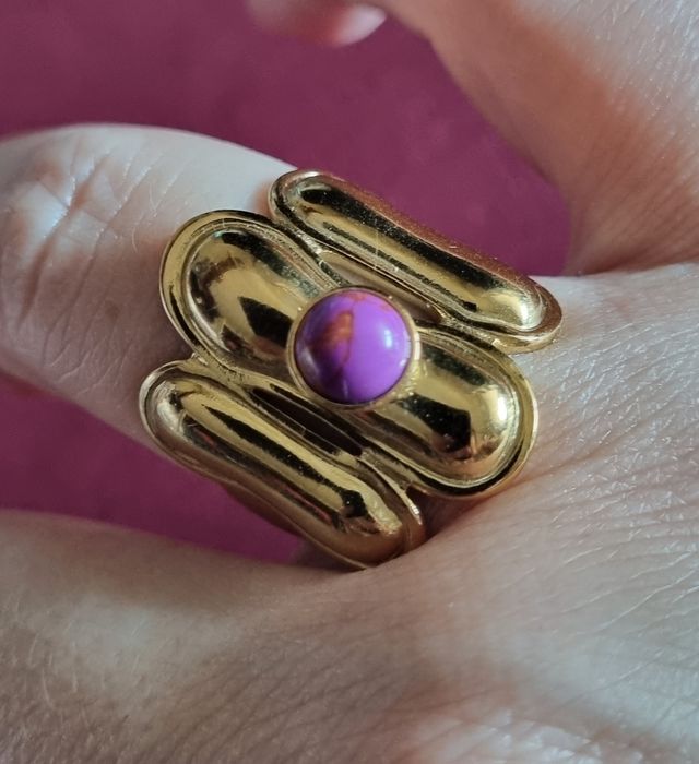 Anel dourado, em aço, com pedrinha redonda lilás. Ajustável