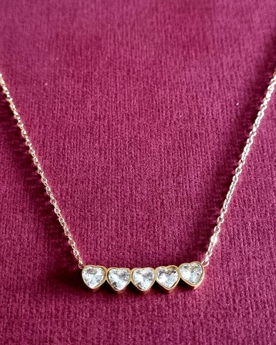 Colar dourado, em aço, com 5 pequenos corações em pedra de vidro.