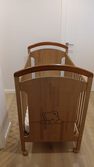 Cama de bebê, em madeira, cor bege.