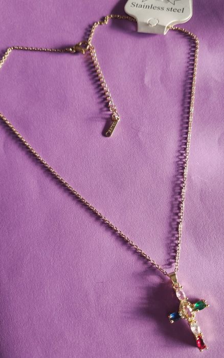 Colar dourado, em aço, com cruz colorida. Tem extensor.