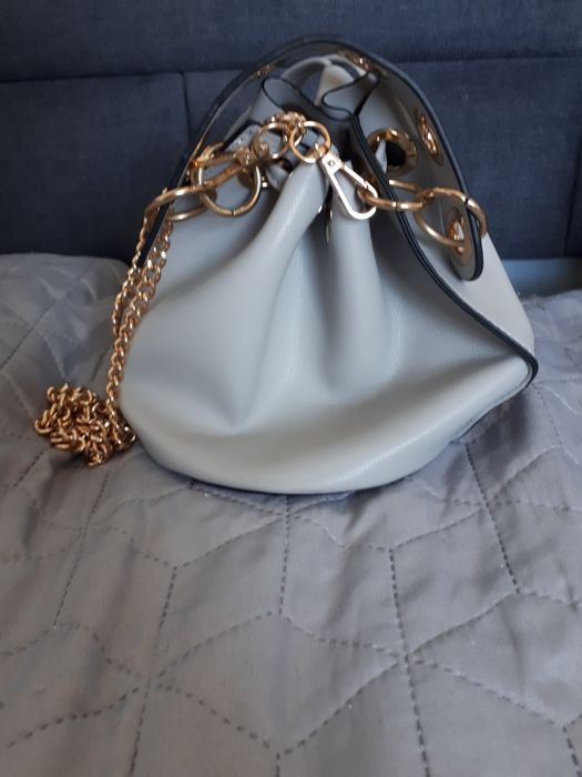 Szara torebka ze złotymi elementami.