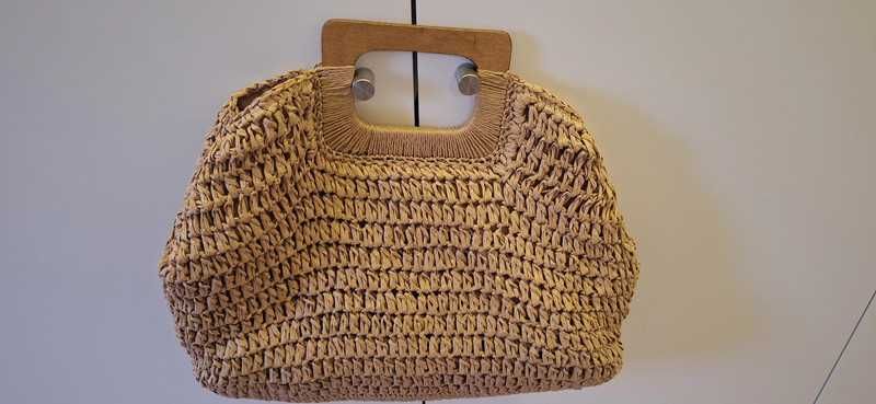 Bolsa de palha trançada com alça de mão.